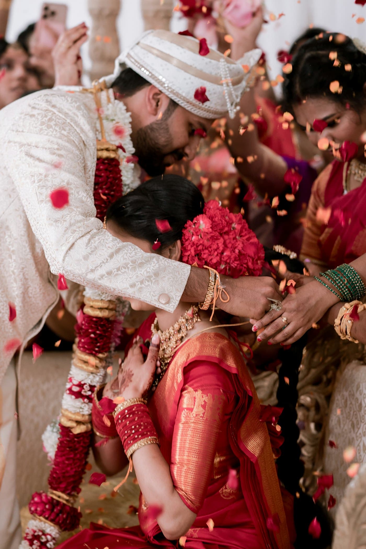 Family members shower a bride and groom with rose petals during the wedding ceremony.
