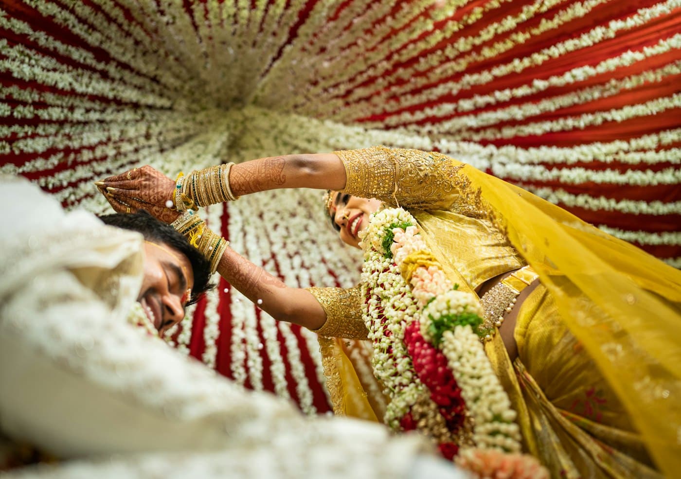 A bride in a yellow sari applies turmeric to the groom during a haldi ceremony.